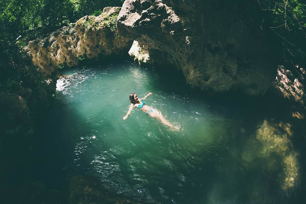 A woman in a swimsuit swims in a mountain river, The girl goes into cold water, Picturesque place of Turkey.