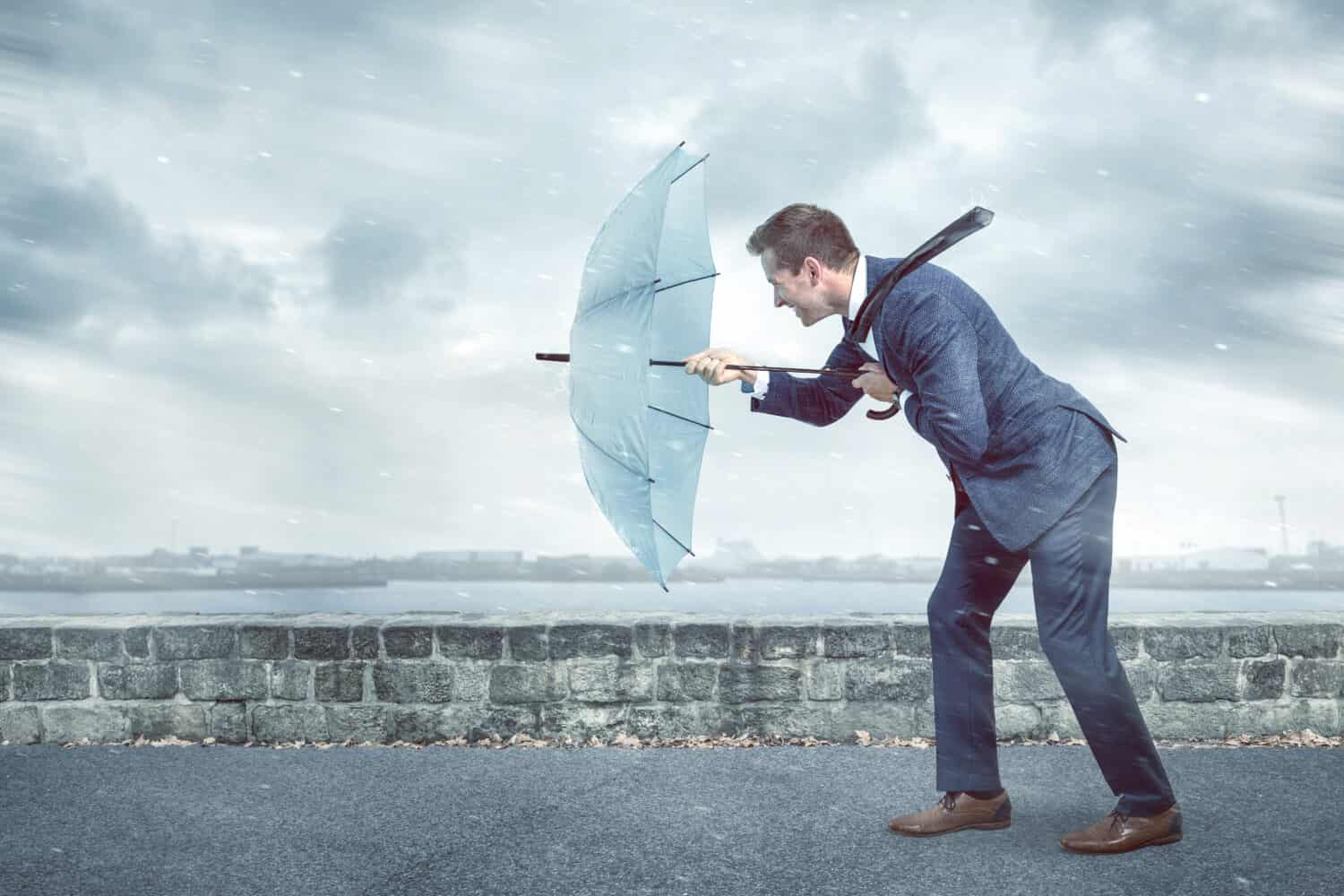 A person struggling against the forceful headwind, symbolizing the relentless power that can disrupt even the simplest of tasks, reminding us of nature's formidable impact.