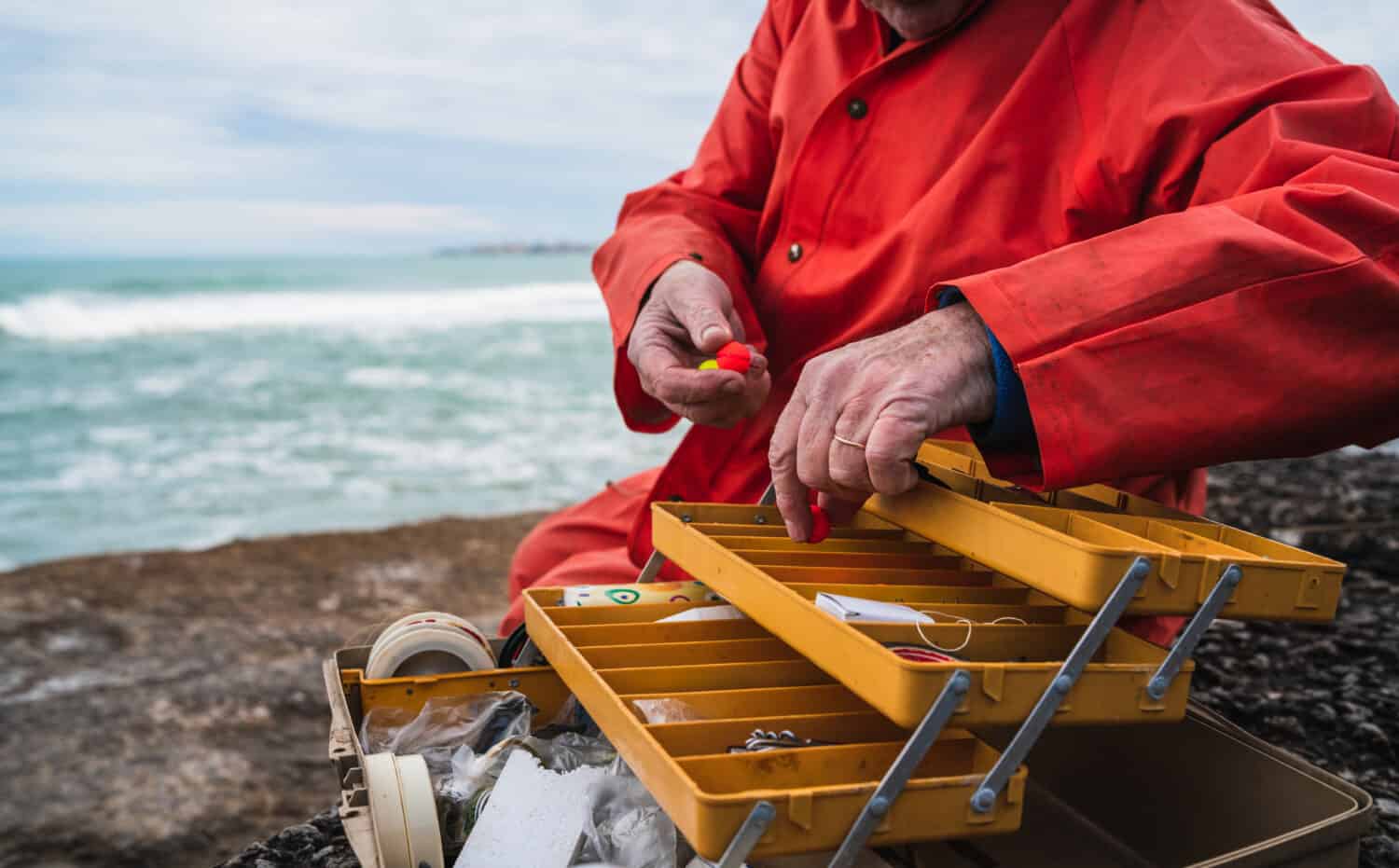 Close-up of a fisherman putting on bait with fishing equipment box. Fishing and sport concept.