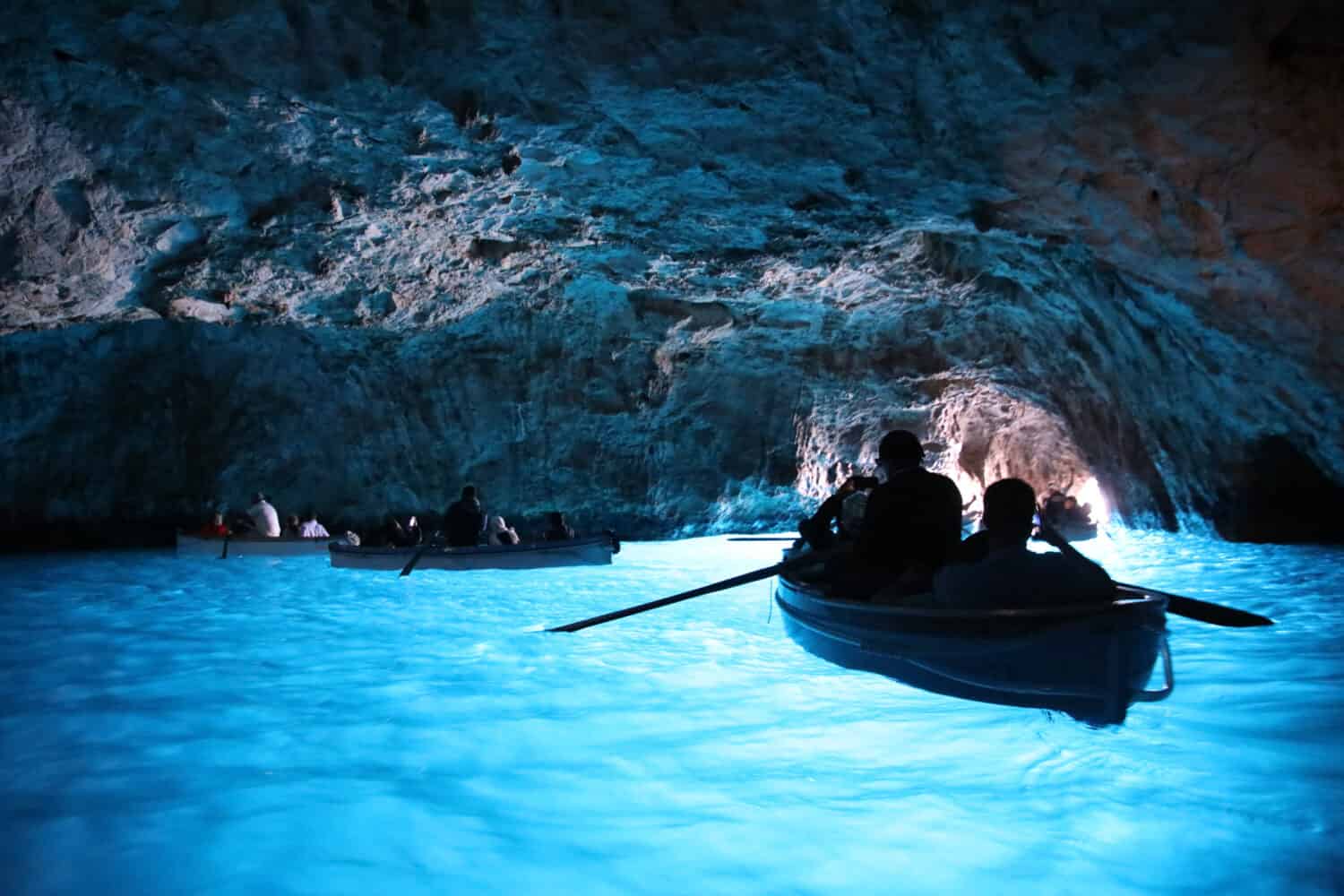 A photo of the Blue Grotto, Italy and people on a boat. 