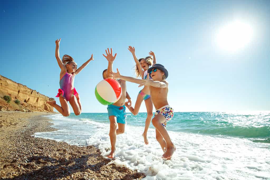 Cute kids having fun on the sandy beach in summer. High quality photo.