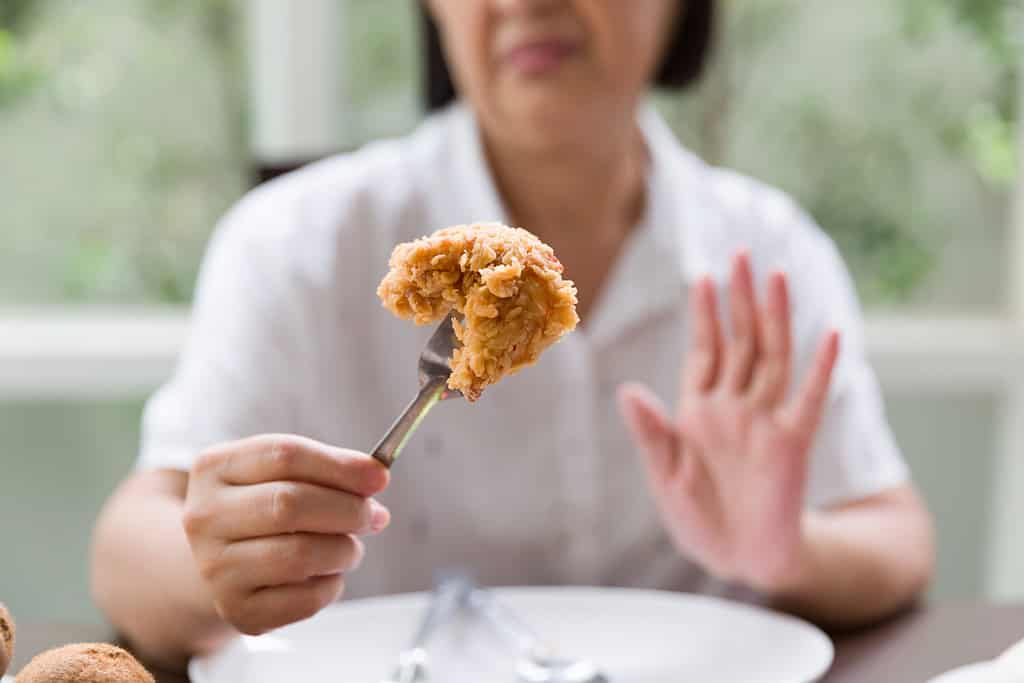 Senior Asian woman don't like fried chicken. Elderly Asian woman don’t eat junk food or fast food. Health care and ageing concept