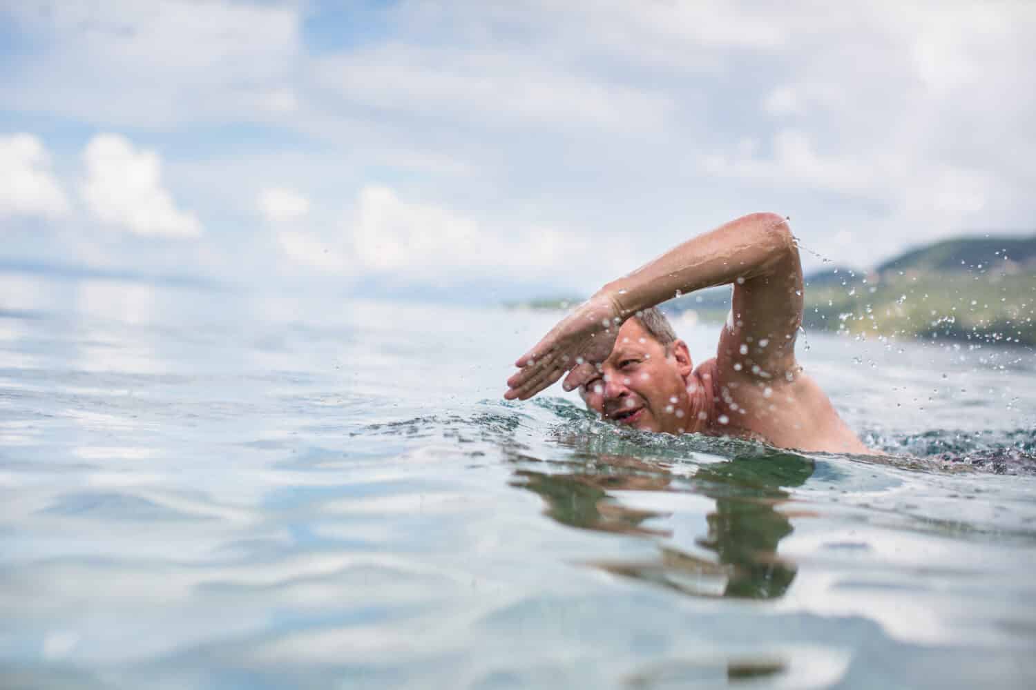 Senior man swimming in the Sea/Ocean - enjoying active retirement, having fun, taking care of himself, staying fit