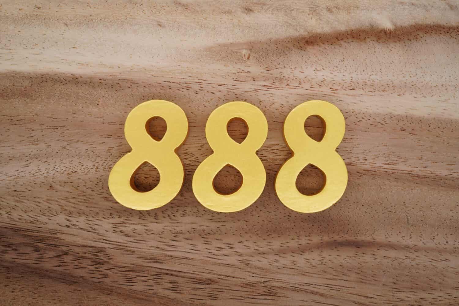 Wooden Arabic numerals 888 painted in gold on a dark brown and white patterned plank background.