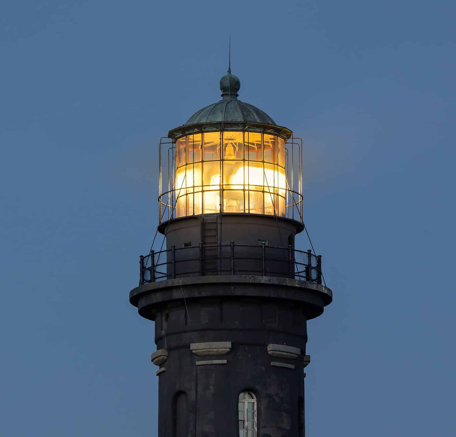 Close up of the lens of a tall stone lighthouse lit up at night. Fire Island, Long Island New York