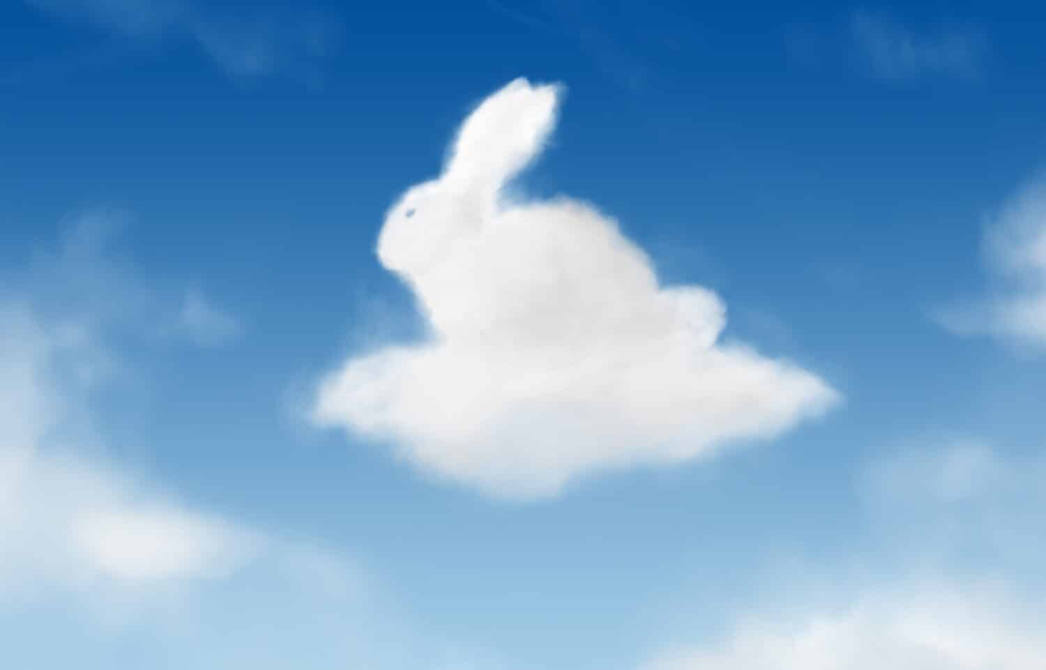 Fluffy Easter bunny rabbit, clouds shaped in blue sky