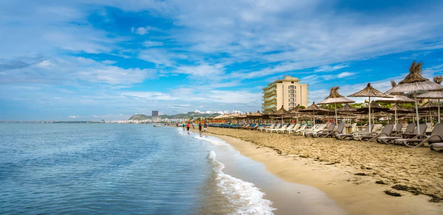 Golem, Durres, ALBANIA. Beach shoreline with sun umbrellas made from straw. A blue sky on the Adriatic Sea.