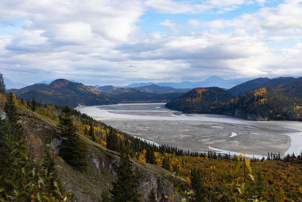 Bend in Chitina river with hills, mountains, and clouds on fall day