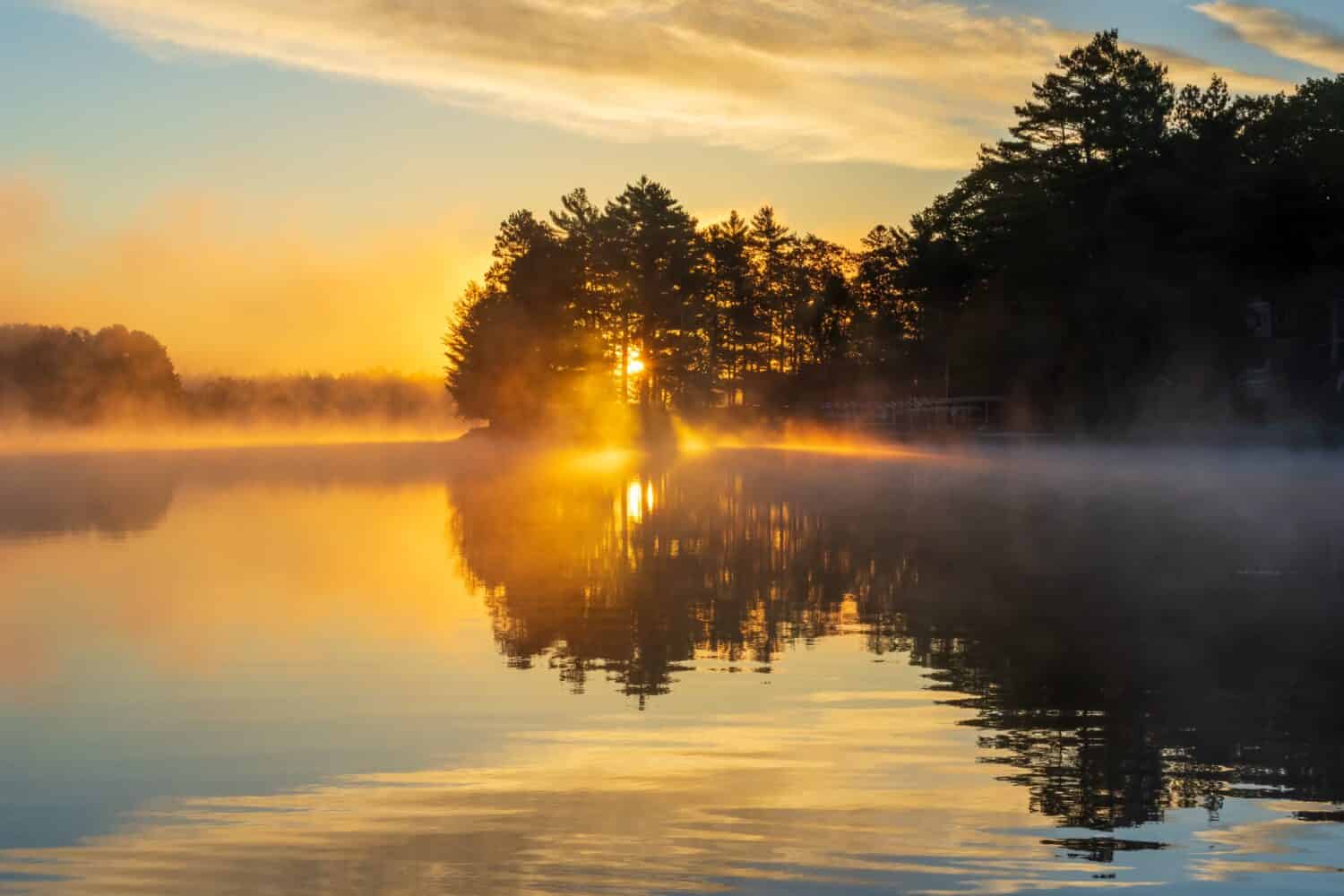 Sun rising over a lake on a foggy morning