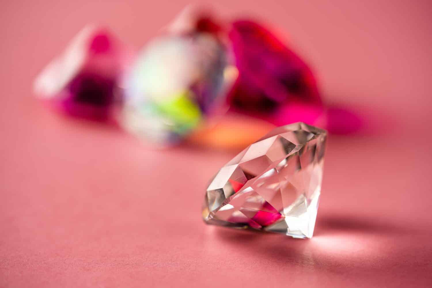 Large White Diamond with Red Pink Diamonds in Background on Pink Paper Shinny Jewelry