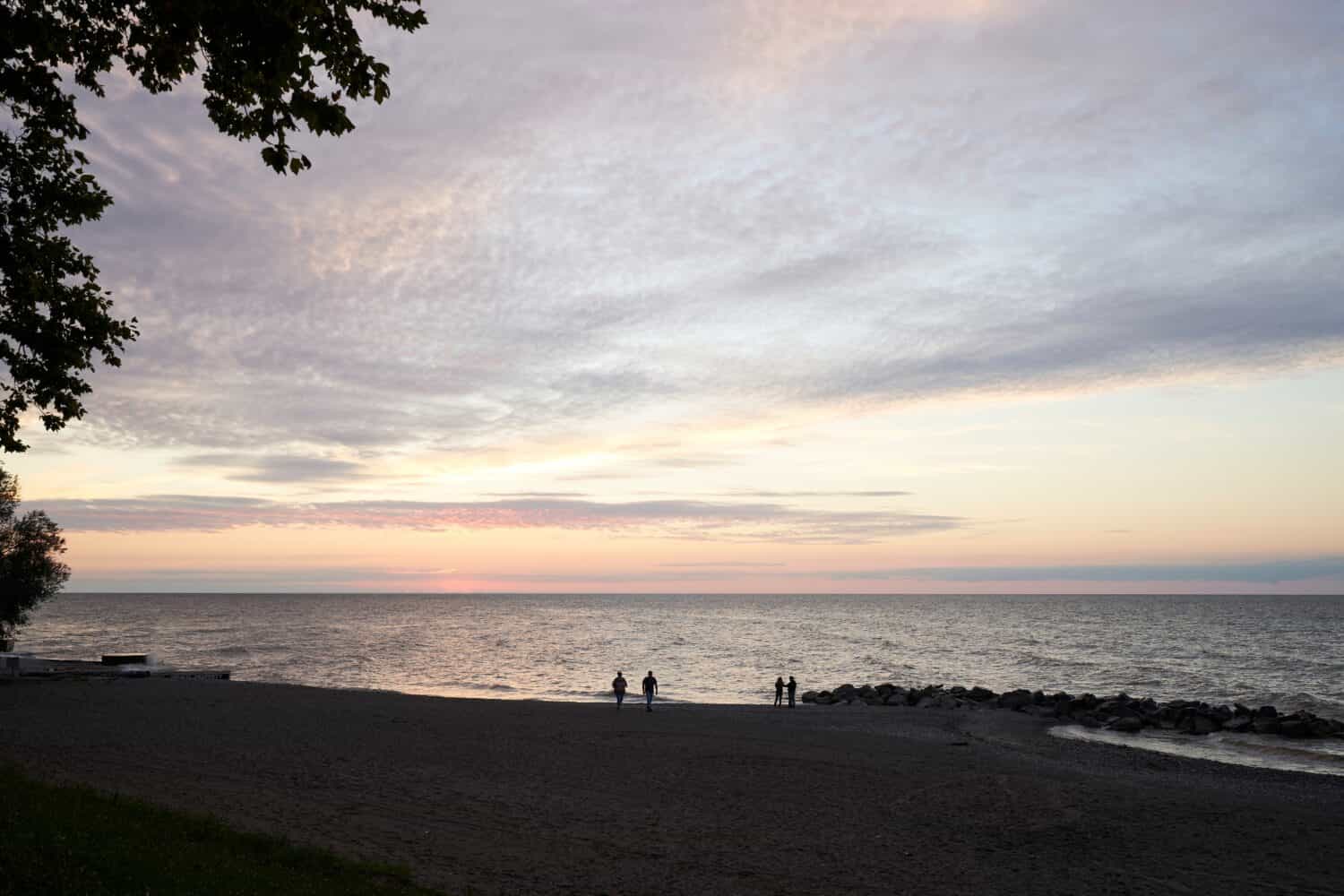 A quiet beach at Madison township park. Madison is a small town in Ohio on Lake Erie. Two couples are walking the coastline.