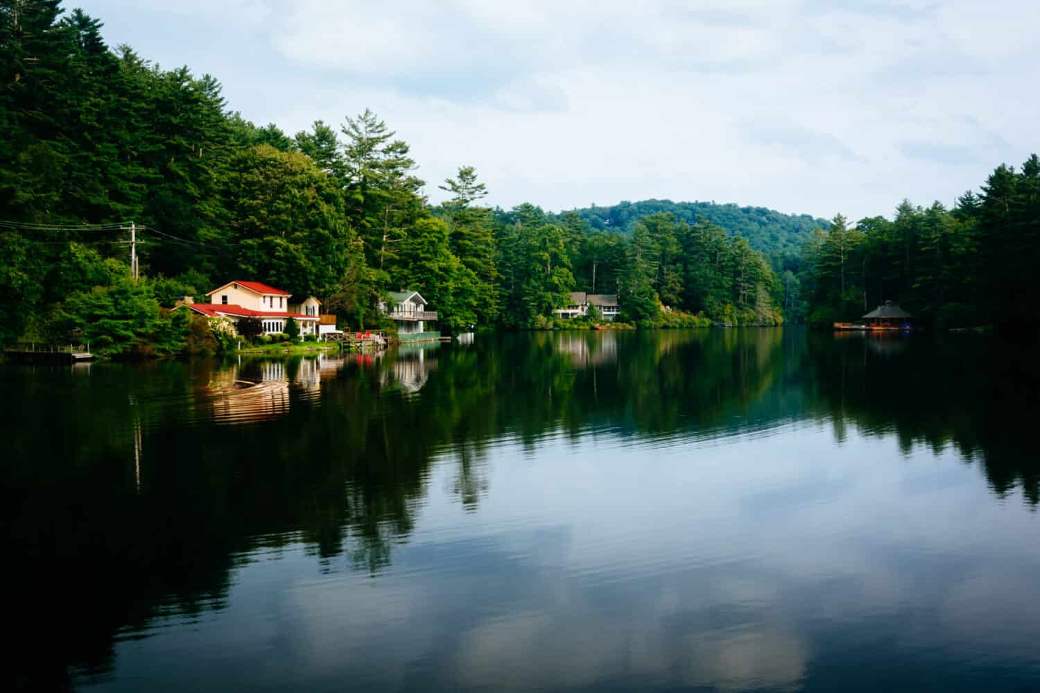 Trees and houses reflecting in Lake Sequoyah, Highlands, North Carolina.
