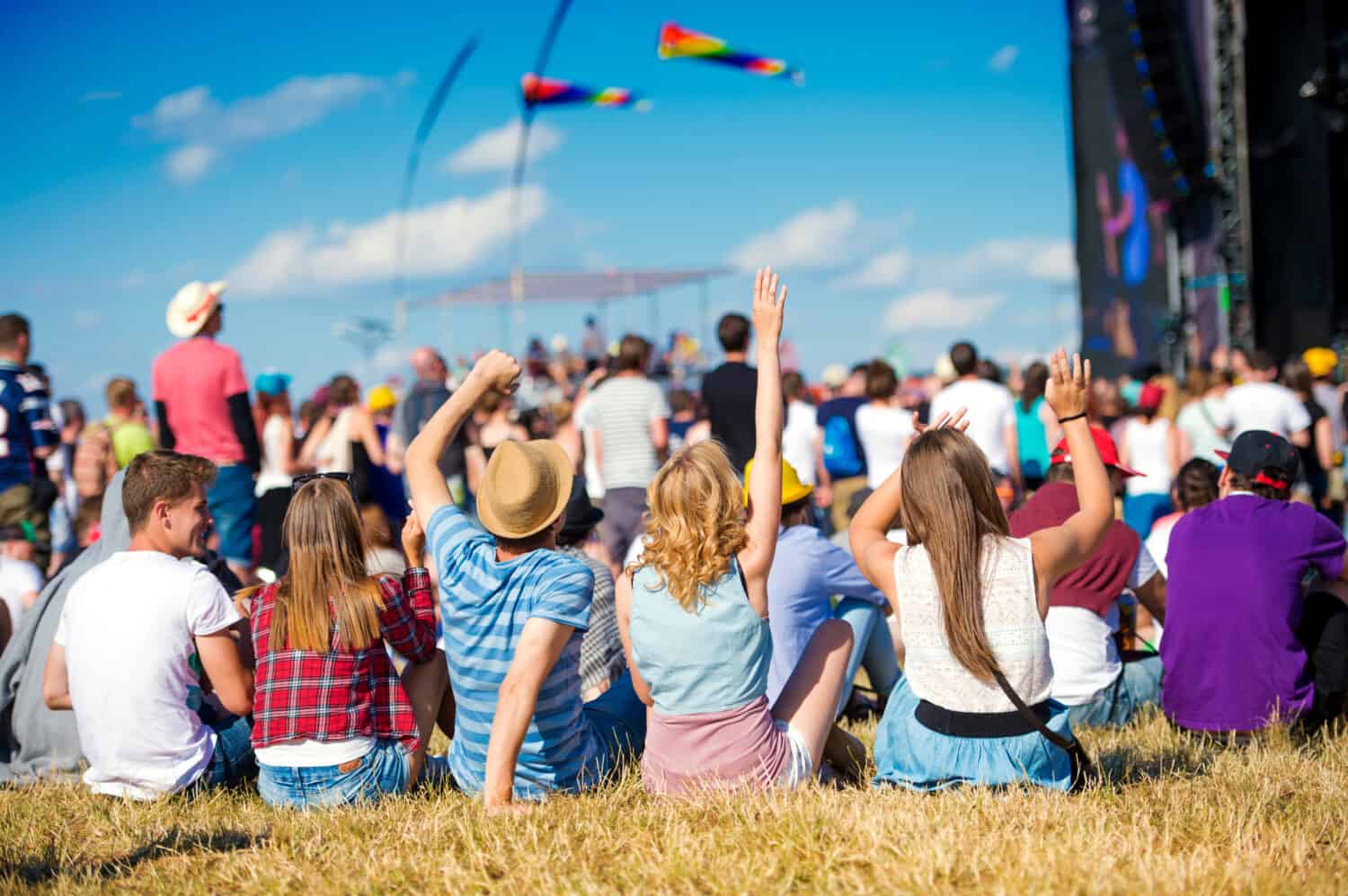 A group of people at an outdoor concert, enjoying the summer weather.