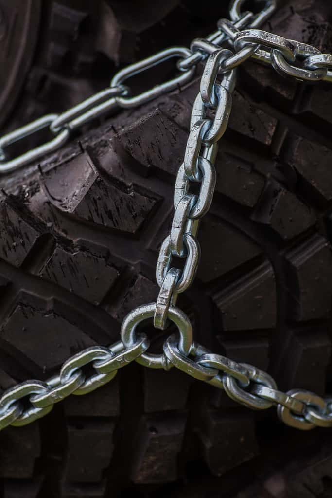 Close up shot of some chains wrapped around a car's tire.