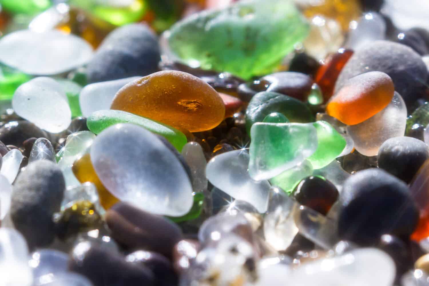 close up of a group of shiny pieces of sea glass on the beach using a star filter to obtain a sparkling effect