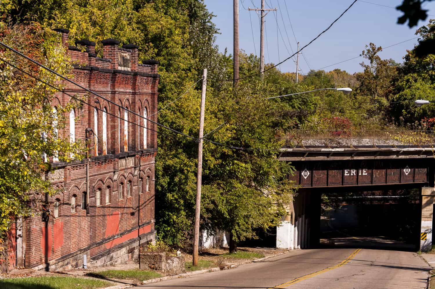 A historic but abandoned brewery with buff red brick with arch detailing lies along a derelict street.