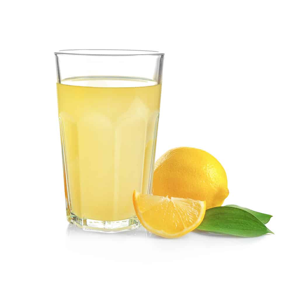 Glass of fresh lemon juice on white background