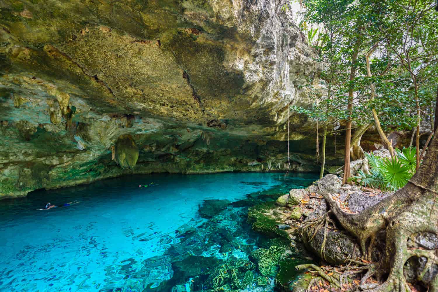 Cenote Dos Ojos in Quintana Roo, Mexico. People swimming and snorkeling in clear blue water. This cenote is located close to Tulum in Yucatan peninsula, Mexico.