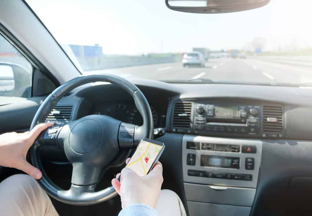 Distracted driver looking at GPS on phone.