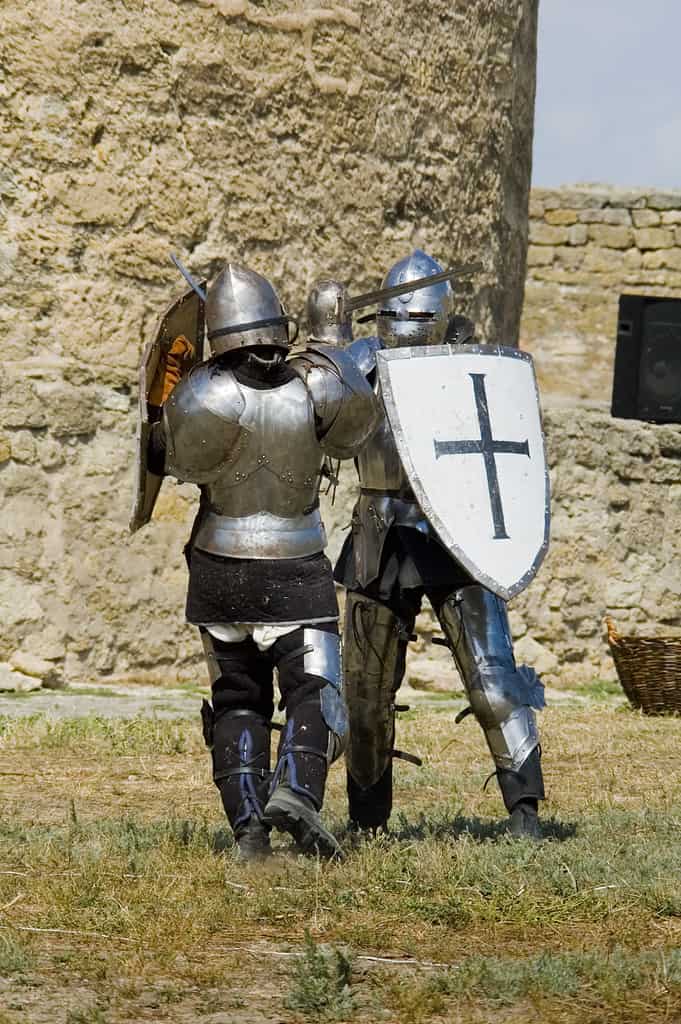 Medieval european knights fighting near citadel wall