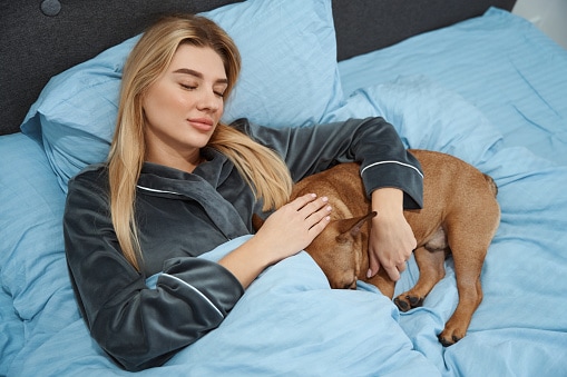 Serene woman dozing off with her dog in bedroom