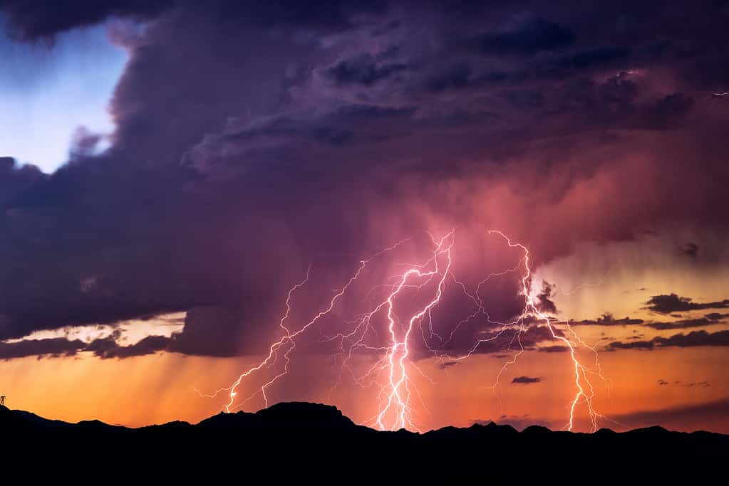 Lightning bolts strike from a sunset storm in Arizona desert