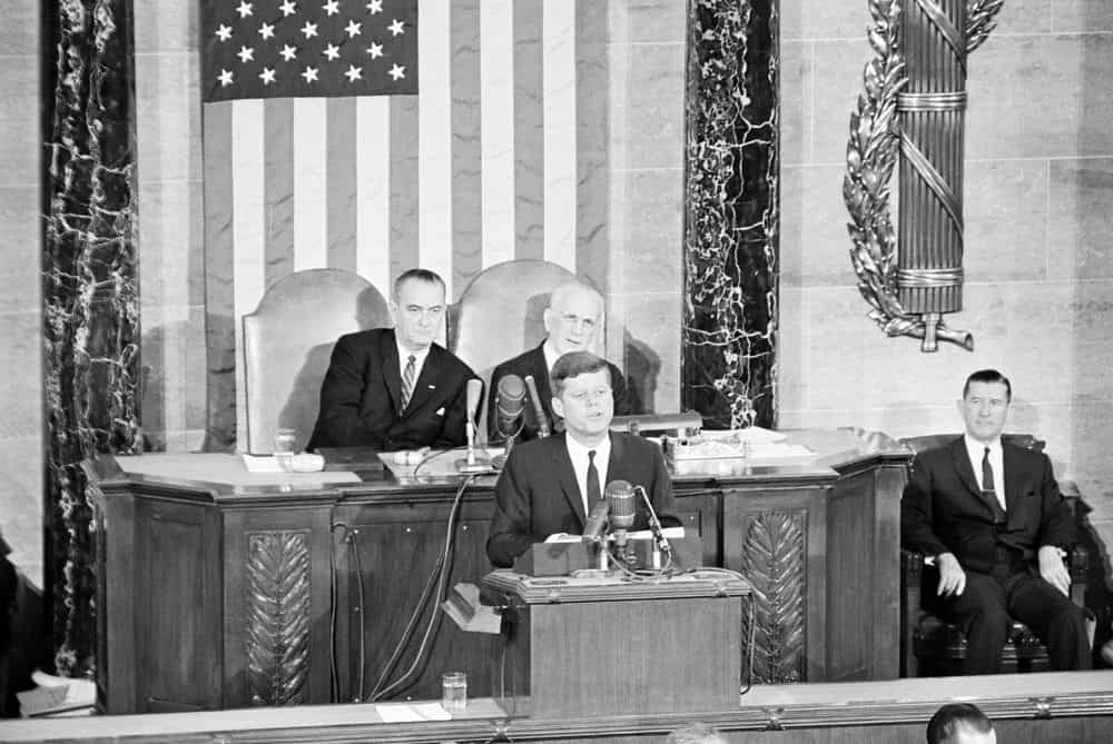 h: President John F. Kennedy delivers his annual address to the Congress on the State of the Union. Vice President Lyndon B. Johnson and Speaker of the House of Representatives John W. McCormack sit behind President Kennedy; Clerk of the House of Representatives Ralph R. Roberts sits at right. House of Representatives Chamber, United States Capitol Building, Washington, D.C. Date 11 January 1962