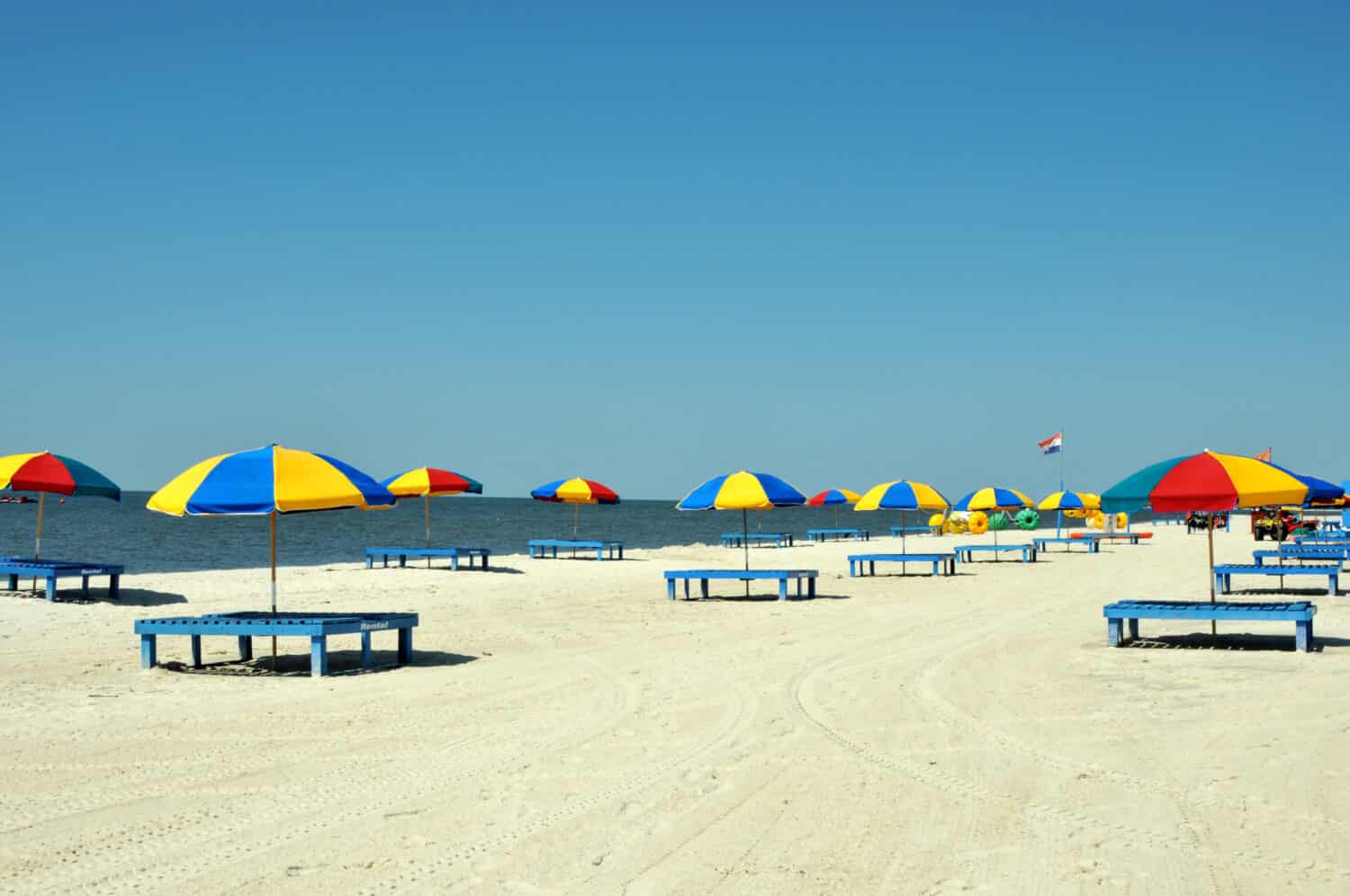 Lounge chairs, umbrellas, and oversized trikes scattered along Biloxi Beach in Mississippi on a spring day.