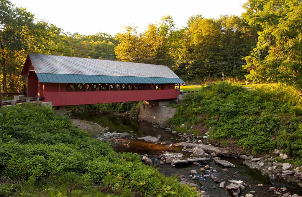 Creamery covered bridge built in 1879 in Brattleboro Vermont. Beautiful historic red covered bridge with a flowing stream of water below it.