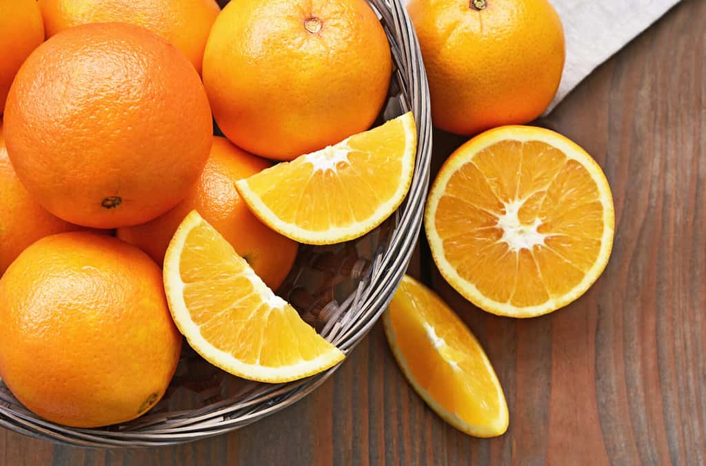 A lot of Navel Orange full and slice in basket on wooden background.