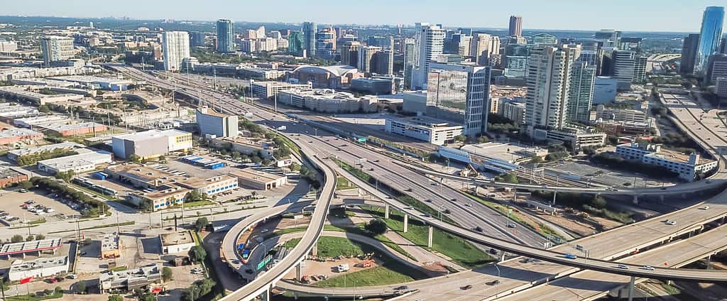 Panorama aerial view highway stack interchange and Dallas Downtown buildings under cloud blue sky. Woodall Rodgers Freeway, Stemmons Freeway, Interstate 35E (I-35E)