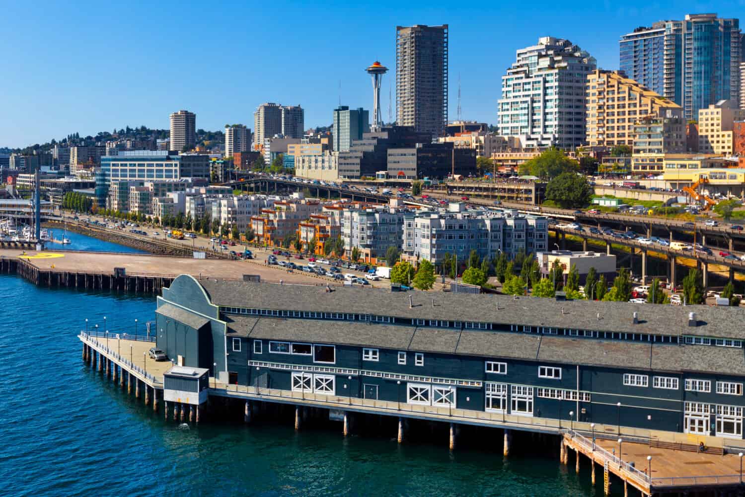 Aerial view of Seattle waterfront and skyline with the Space Needle in the background. There's traffic on the waterfront Alaskan Way Viaduct, the elevated double-decker Highway 99.