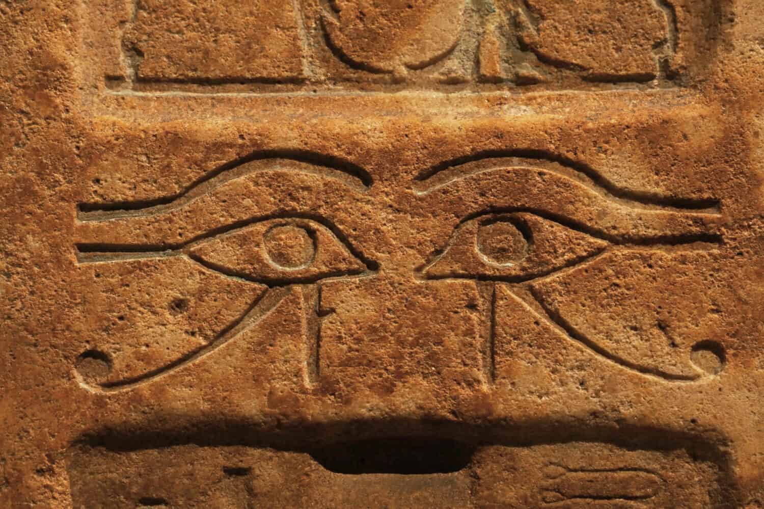 Close up background of antique stone wall with carved ancient Egyptian bas relief of wadjet, Eye of Ra or Horus, front view