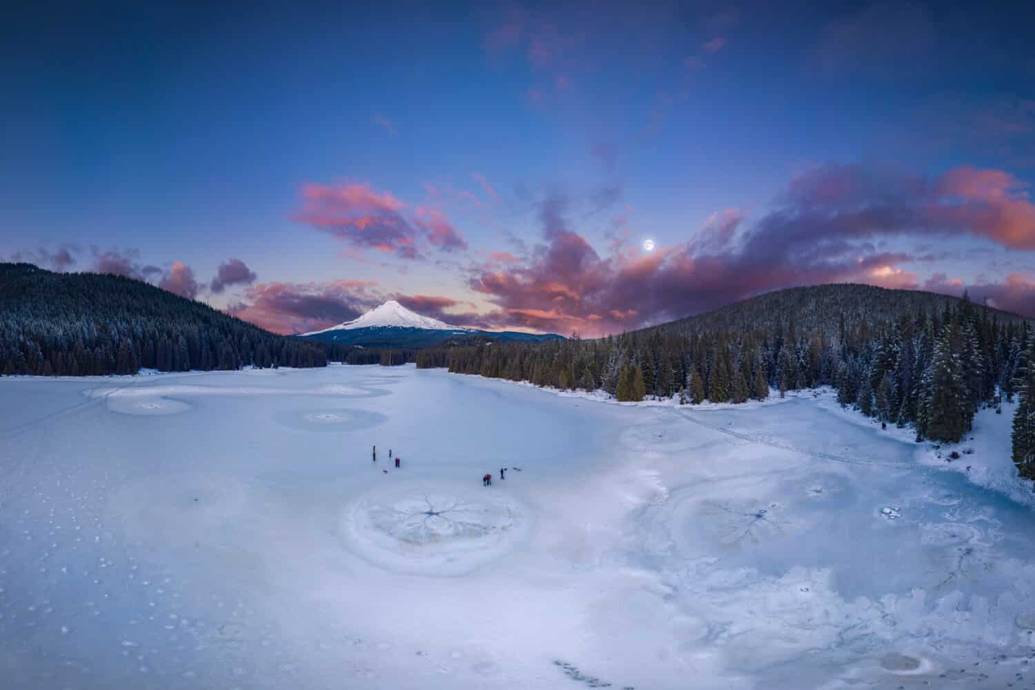 This is a panoramic sunset view of the frozen Trillium Lake and Mt Hood.