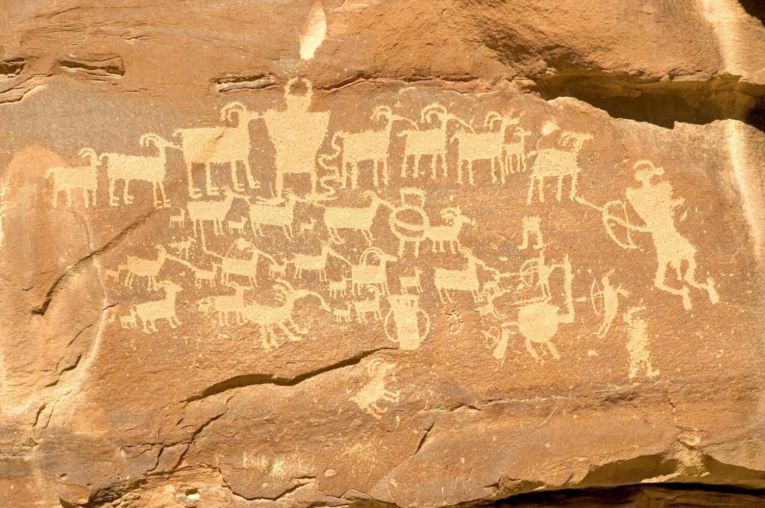 Fremont Indian hieroglyph in Nine Mile Canyon (near Price, Utah) featuring hunters with bows and arrows, a horned shamanic figure, and a shield figure in the middle of the bighorn sheep.
