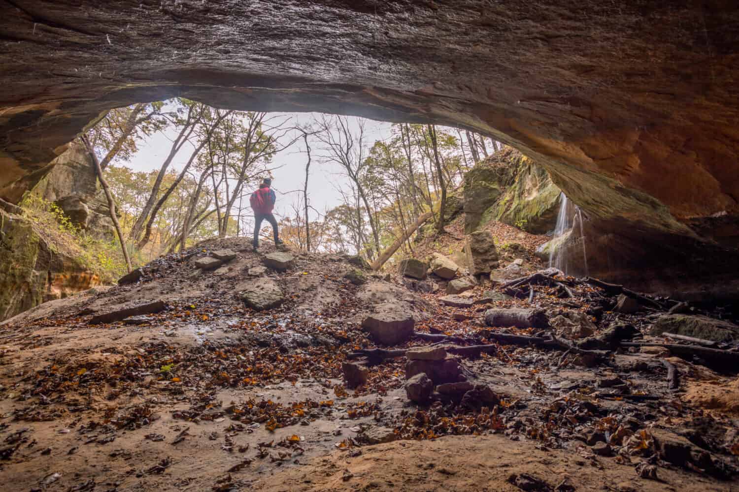 A Wide Shot of a Man Looking Out from a Cave into the Wilderness of Wisconsin during an Autumn Day