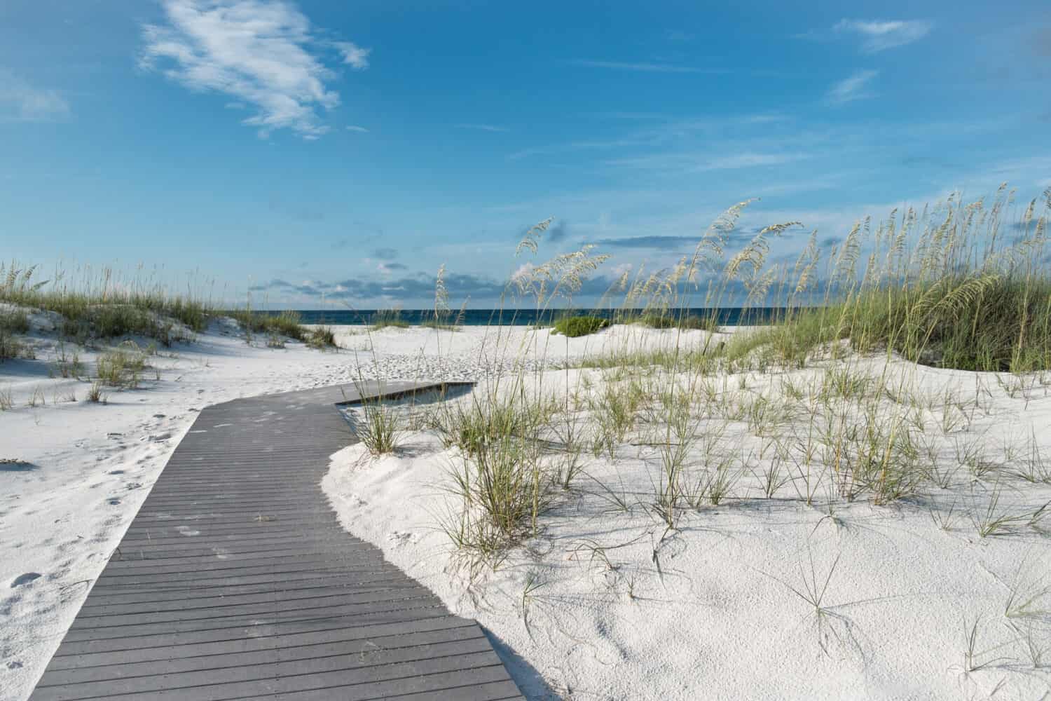 Small rustic boardwalk footpath through snow white sand dunes at a pristine Florida beach.