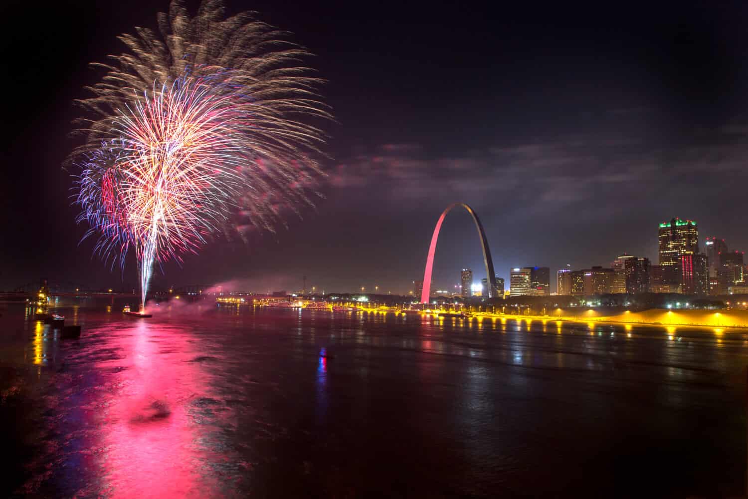colorful fireworks explode in the night sky over the mississippi river and gateway arch in st louis during the fourth of july celebration