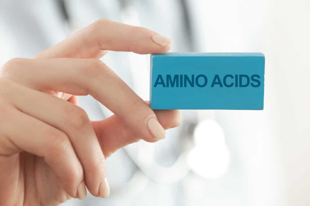 Doctor advises. Medical worker holds AMINO ACIDS signs.