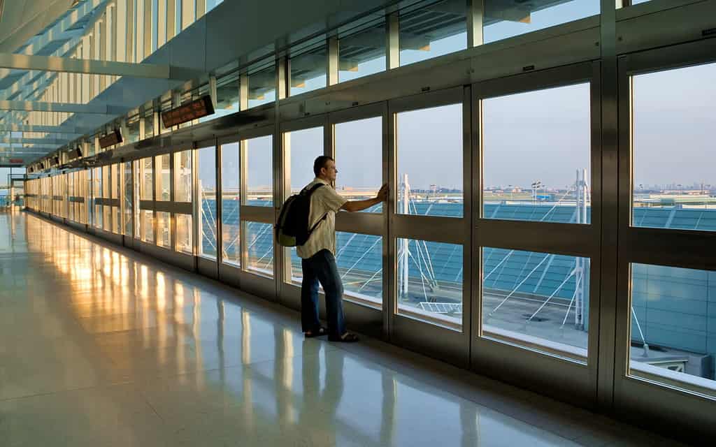 Man standing by a window and waiting his flight, Pearson International Airport, Toronto, Canada.