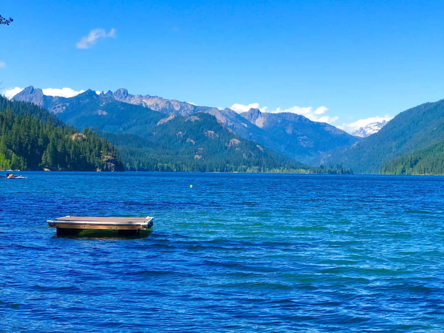 A serene view of Little Kachess Lake, nestled among lush green trees and surrounded by mountains