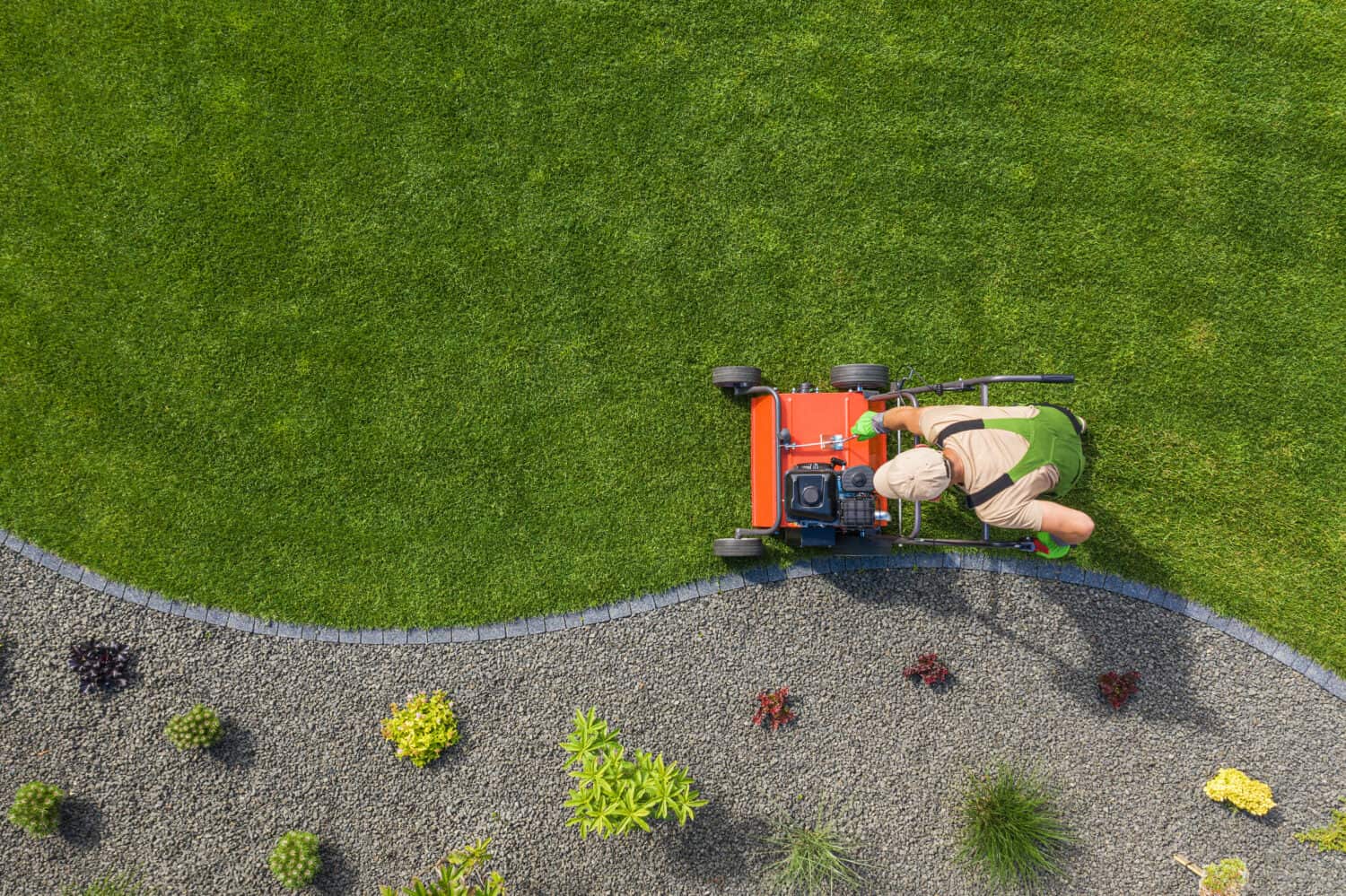 Powerful Gasoline Lawn Aerator Job For Controlling Lawn Thatch, And Reducing Soil Compaction. Backyard Grass Field Maintenance. Caucasian Gardener in His 40s. Aerial View.