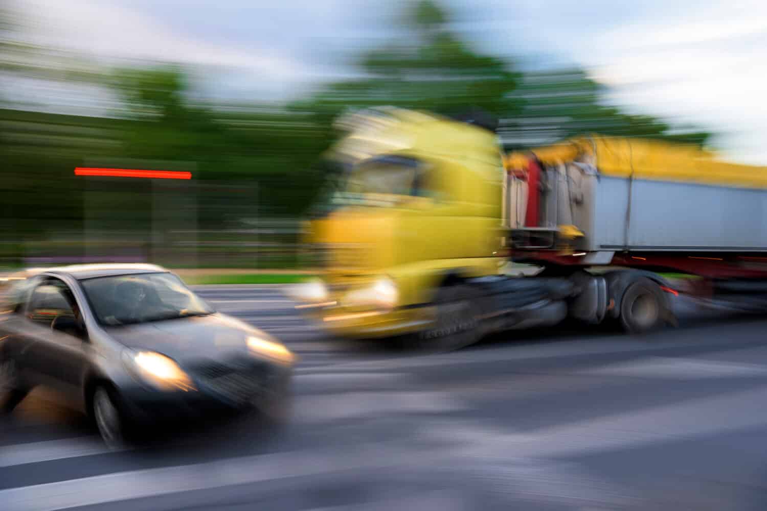 Dangerous city traffic situation between a car and a truck in motion blur. Defocused image