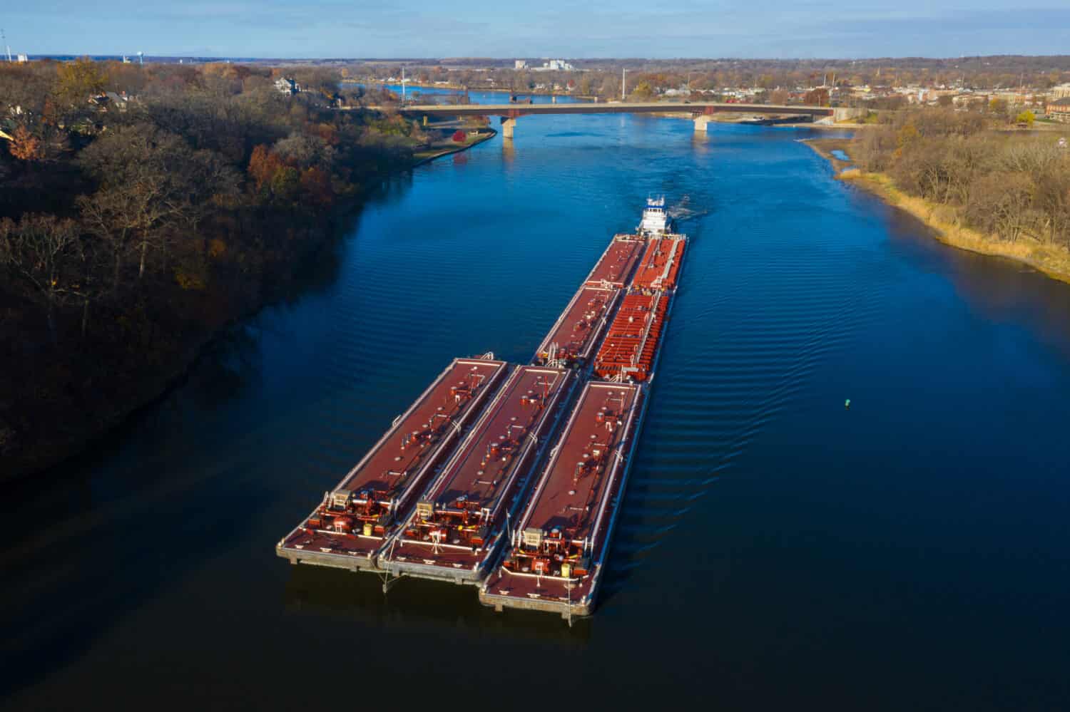 A red barge ships cargo down the Illinois River near Ottawa, Illinois. Aerial photograph via drone.