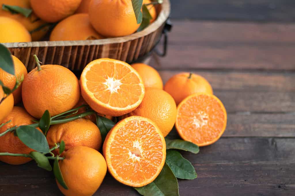 Orange fruit with green leaves on the wood. Home gardening. Mandarine oranges. Tangerine oranges. Orange color. Fresh orange juice.