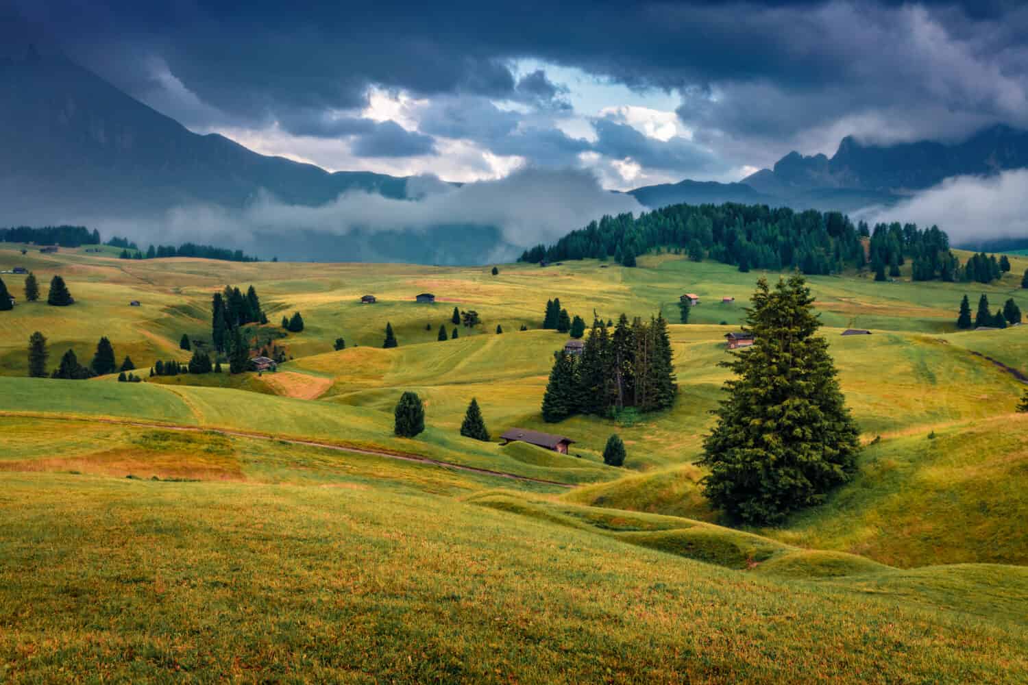 Dramatic summer scenery. Low overcast view of Compaccio village, Seiser Alm or Alpe di Siusi location, Bolzano province, Dolomite Alps, South Tyrol, Italy, Europe. Traveling concept background.