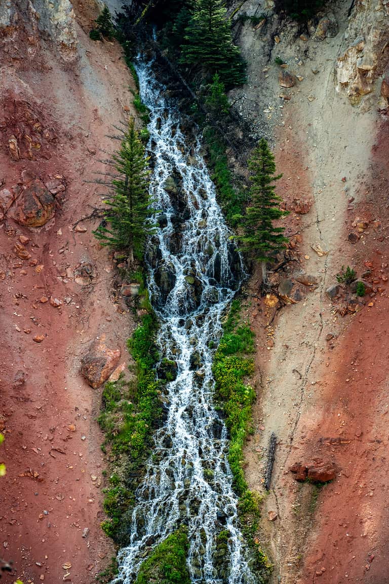 Silver Cord Cascade Tumbles over Red cliffs in Yellowstone
