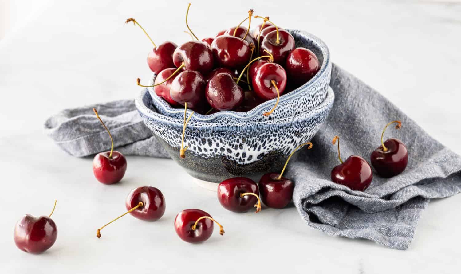 Two pottery bowls stacked on top of each other filled with chelan cherries.