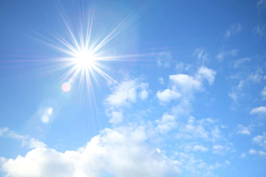 Blue sky with white fluffy clouds and sun reflection. Sunny background. Sun appear directly above Thailand. The afternoon summer sun shines on a beautiful sky with clouds. Hot weather, summer season.