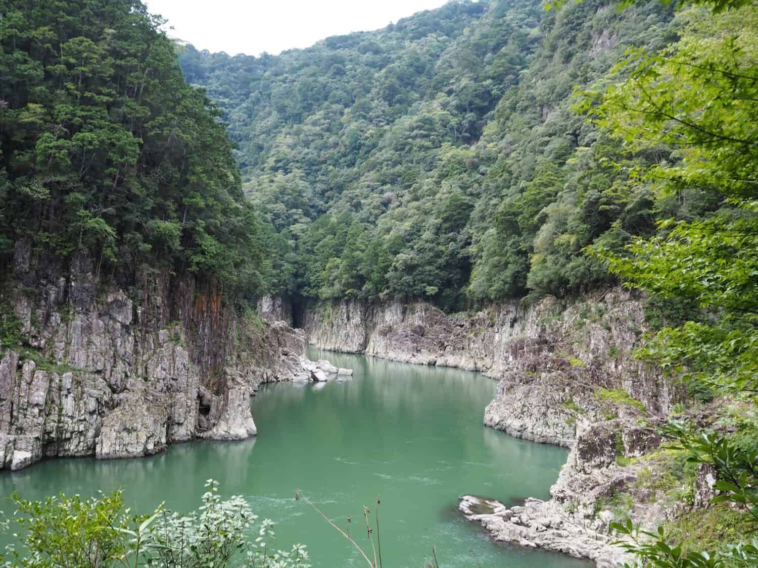 View of beautiful valley with green river water and steep cliffs (Dorokyo Gorge, Kumano River, Japan)